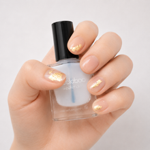 Load image into Gallery viewer, Peelaboo Clean Look Gold Kit — hand with gold foil nail art next to clear base and top coat peel-off nail polish bottle