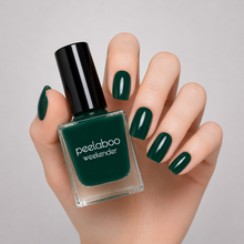 Load image into Gallery viewer, Hand with deep green nails holding a bottle of peelaboo weekender nail polish against a gray background