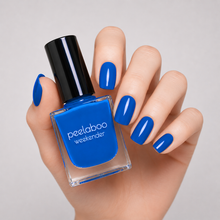 Load image into Gallery viewer, Hand with bright blue nail polish holding a bottle of peelaboo weekender blue nail polish.