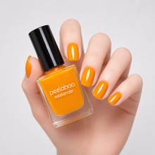 Load image into Gallery viewer, Hand holding a bottle of peelaboo nail polish with matching orange nails on a light gray background