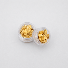 Load image into Gallery viewer, Two clear jars filled with gold flakes on a light gray background
