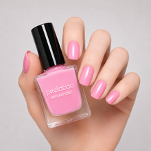 Load image into Gallery viewer, Hand holding a bottle of pastel pink nail polish with matching nails against a neutral background
