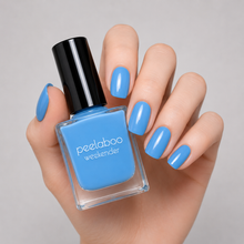 Load image into Gallery viewer, Hand holding a bottle of peelaboo nail polish with matching  pastel blue nails on a gray background
